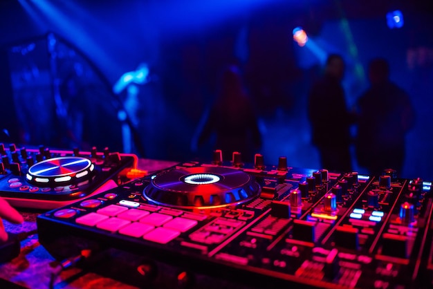 Console de DJ para mixar músicas com pessoas embaçadas dançando em uma festa de boate