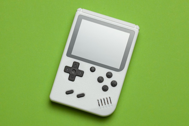 Console de jogos antigo. O gamepad é branco sobre um fundo verde.