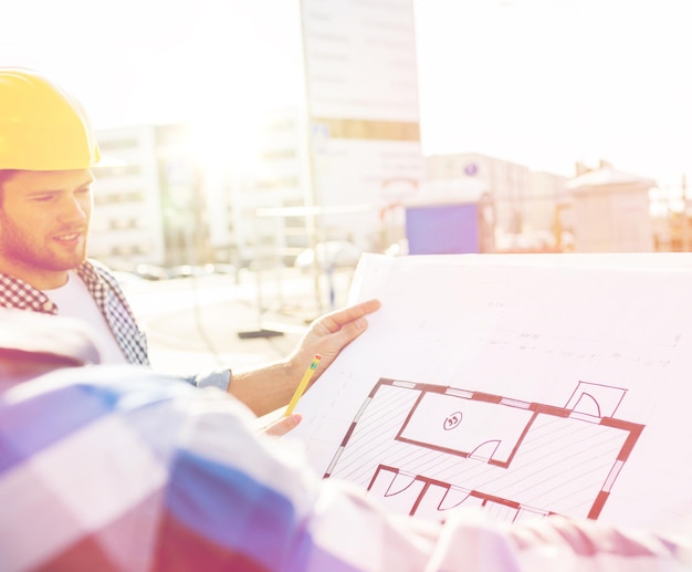 construção, construção, desenvolvimento, trabalho em equipe e conceito de pessoas - close-up de construtores com planta no canteiro de obras