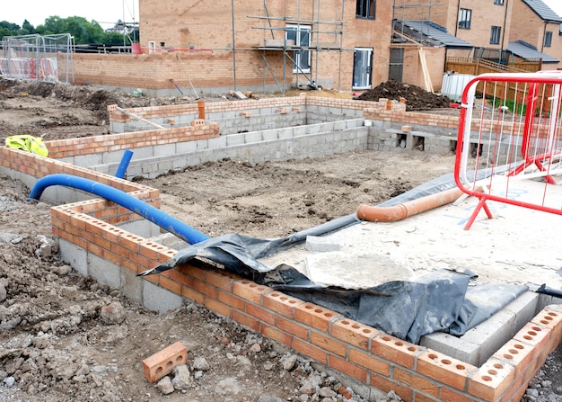 Construção de casa em andamento no local de desenvolvimento habitacional com parte subterrânea da parede concluída