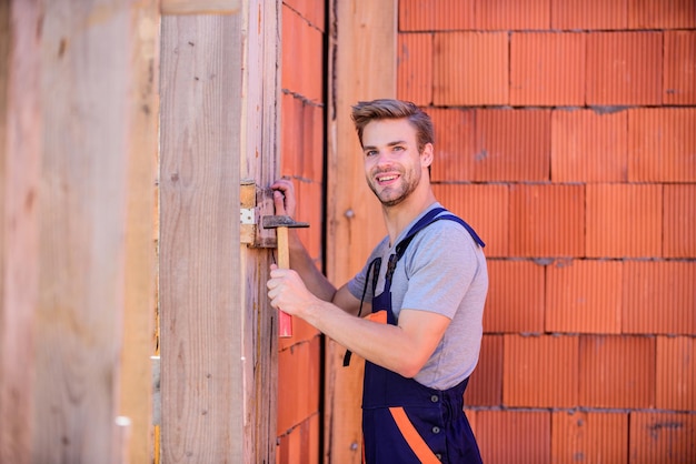 Construção de casas futuras e engenheiro de construção construir com ferramenta de martelo arquiteto reparar e consertar construtor de homem em roupas de trabalho trabalhador parede de tijolo fundo reparador profissional capacete