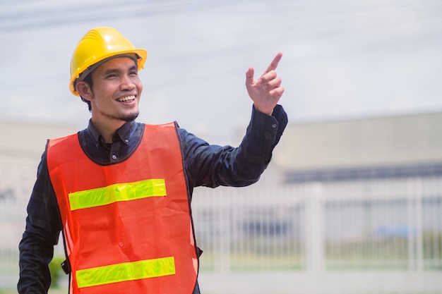 Construção de engenheiro asiático confiante na construção do local e arquiteto civil de pesquisa por empresa empreiteira com fundo de fábrica de capacete de segurança