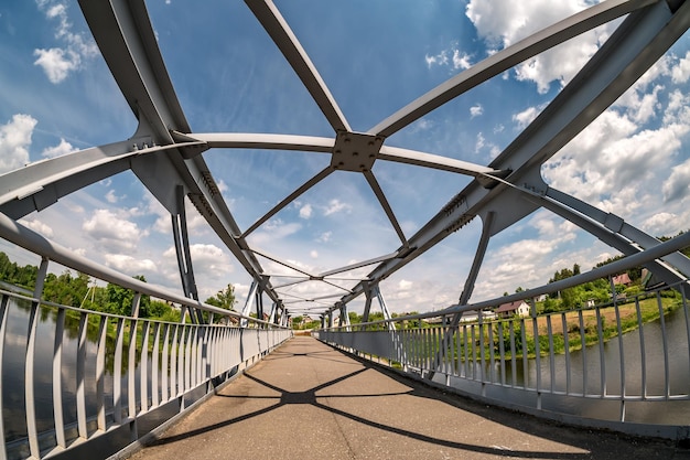 Construção de estrutura de aço de ferro da ponte pedonal através da vista de grande angular do rio