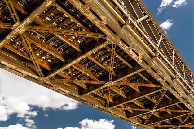 Foto construção de grade de aço de uma ponte ferroviária em um fundo de céu azul com nuvens brancas