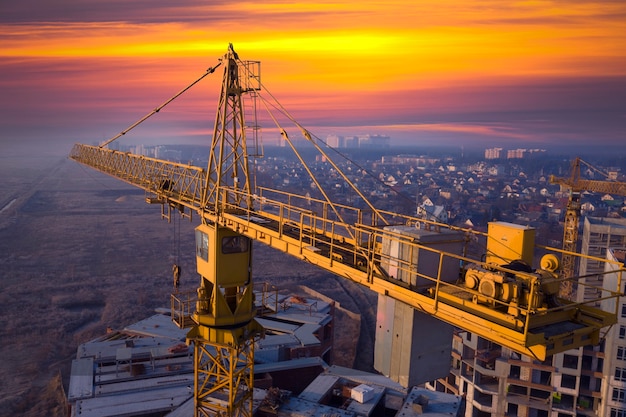 Construção de novos edifícios de vários andares. guindaste de construção ao amanhecer em um canteiro de obras. vista do drone. névoa da manhã no horizonte.