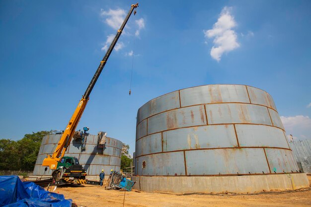 Construção de um guindaste de torre de petróleo, grandes tanques de óleo no fundo.