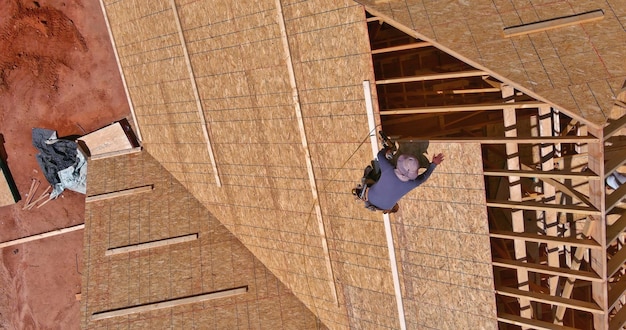 Construção trabalhando no revestimento do telhado de madeira compensada de um novo projeto residencial residencial um aeri