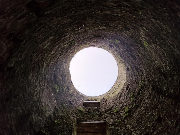 La construcción antigua del pozo de piedra desde el interior se cae en el pozo