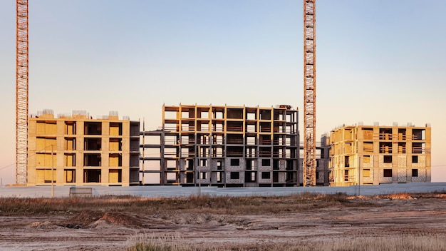 Construcción de una casa de estructura de paneles al atardecer utilizando una grúa torre. luz de fondo Trabajar de noche en la construcción de un edificio residencial.