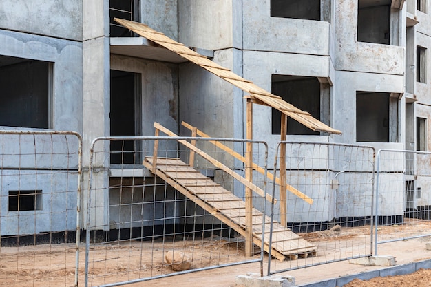 Construcción de una casa de hormigón armado con paneles de varios pisos. Rampa segura a la entrada del edificio. Seguridad en obra.