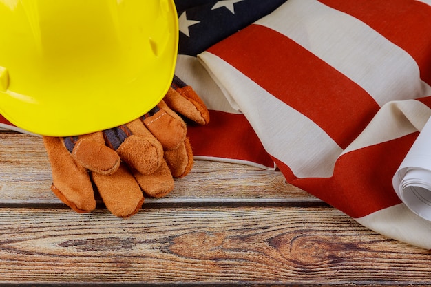 Construcción casco amarillo y guantes de cuero en el feliz Día del Trabajo EE.UU. un feriado federal de la bandera de Estados Unidos de América fondo de madera patriótica