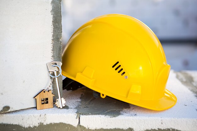 Construcción casco amarillo y llave de casa en ventana de vivienda hecha de bloques de hormigón poroso. Construcción llave en mano, futura vivienda, ingeniería, edificación. Seguridad del trabajo. Copia espacio