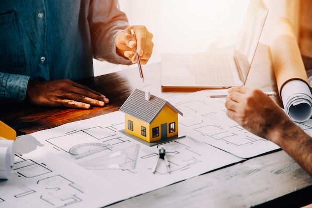 Construcción y concepto de estructura del ingeniero que trabaja dibujando en el plan de trabajo reunión para el proyecto trabajando con el socio en la construcción de modelos y herramientas de ingeniería en el concepto de construcción del sitio de trabajo