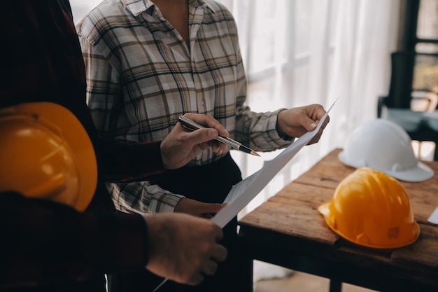 Construcción y concepto de estructura del ingeniero que trabaja dibujando en el plan de trabajo reunión para el proyecto trabajando con el socio en la construcción de modelos y herramientas de ingeniería en el concepto de construcción del sitio de trabajo