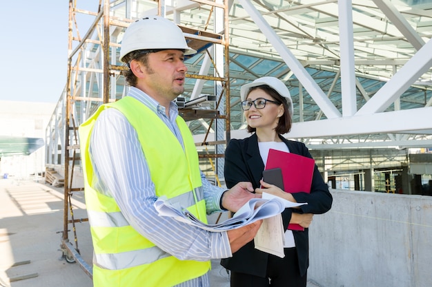 Construcción, constructores de hombre y mujer en el sitio de construcción, equipo de gente industrial.