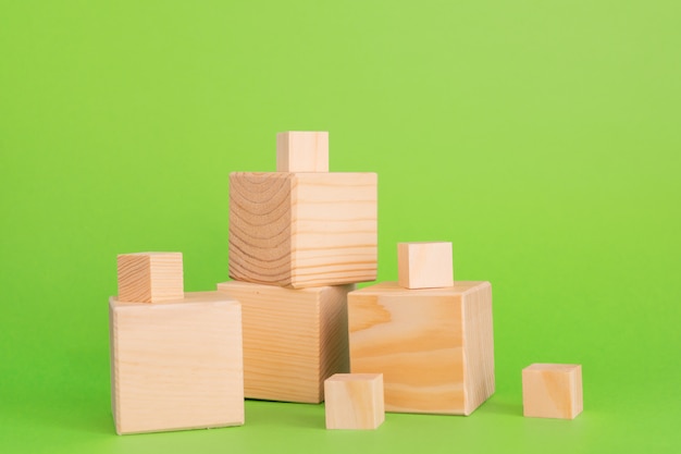 Construcción de cubos de madera sobre fondo verde con espacio de copia. Composición de la maqueta para el diseño