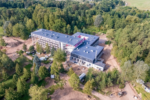 Construcción de un edificio de varios pisos de hotel o clínica de sanatorio en medio de un bosque desde la vista de un pájaro