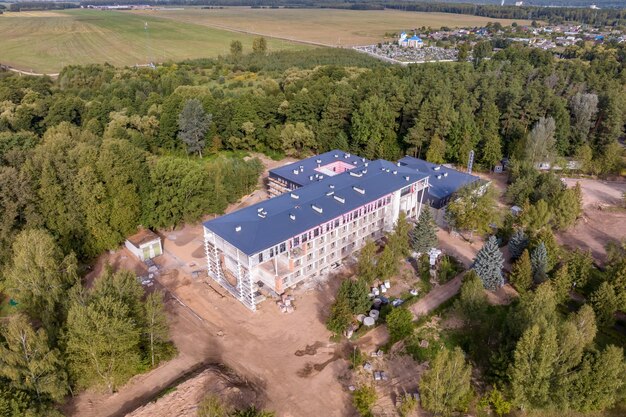 Construcción de un edificio de varios pisos de hotel o clínica de sanatorio en medio de un bosque desde la vista de un pájaro