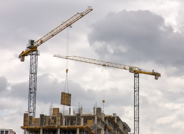 Construcción de edificios de varios pisos con Grúa. Los trabajadores trabajan en la construcción de objetos.