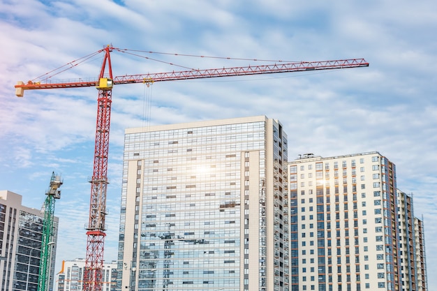 Construcción de grúas y rascacielos de vidrio con reflejo de sol, venta de inmuebles para la población.