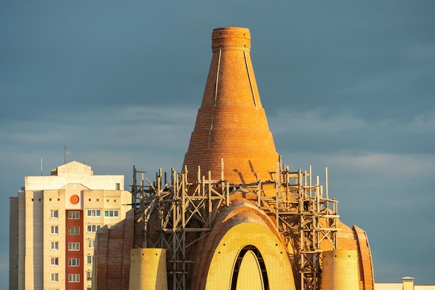 La construcción de la iglesia contra la puesta de sol Andamios fijados alrededor de la cúpula de ladrillo de la nueva iglesia El sitio de construcción de un templo ortodoxo