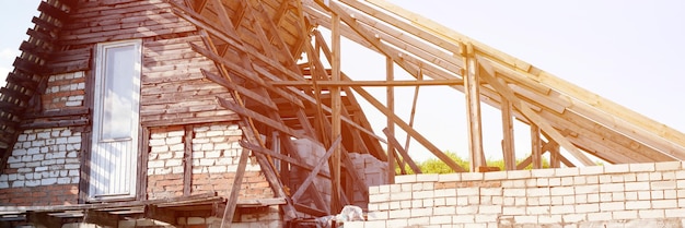 construcción inacabada y construcción de una casa de bricolaje de ladrillo con techo de madera con sus propias manos en el pueblo rural en la agricultura. ampliación y terminación de la casa particular. bandera. llamarada