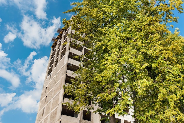 construcción de una nueva casa monolítica de varios pisos en el fondo de un árbol verde