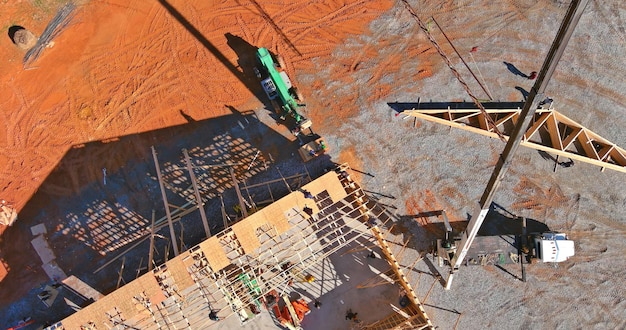 En construcción en el techo, una grúa de vista superior aérea sostiene vigas de techo de estructura de madera