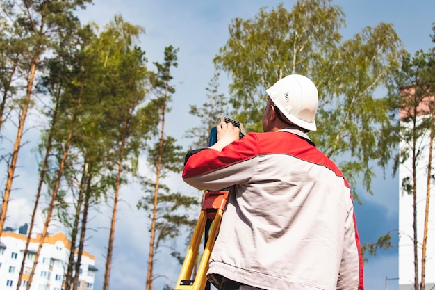 Construcción de una zona residencial Replanteo geodésico Agrimensor en un gran sitio de construcción Un hombre con un tacómetro durante el trabajo Makshader