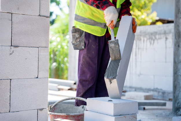 Constructor de albañiles utilizando mortero de cemento para colocar los ladrillos ligeros. en el sitio de construcción