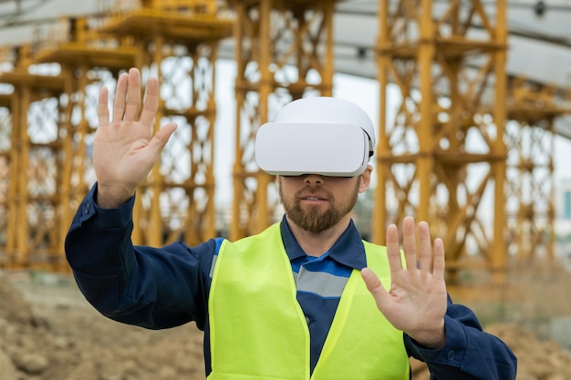 Constructor contemporáneo en auriculares vr tocando la pantalla virtual mientras trabaja al aire libre