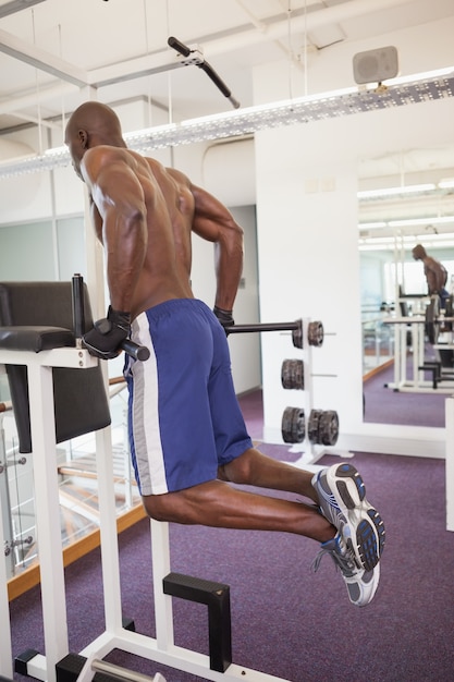 Constructor de cuerpo masculino haciendo pull ups en el gimnasio