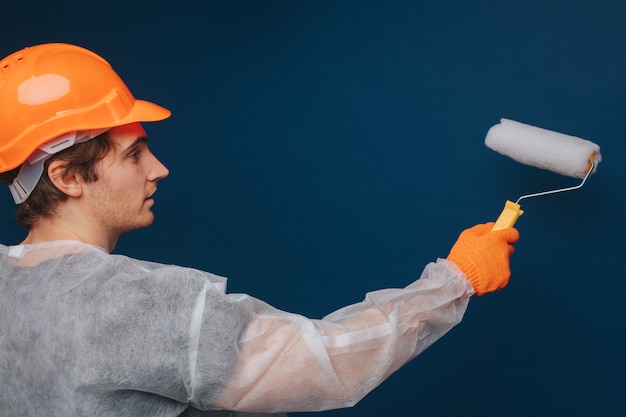El constructor está usando un rodillo para pintar la pared.