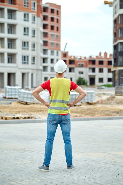 Foto constructor experimentado en un casco de seguridad examinando un área de construcción