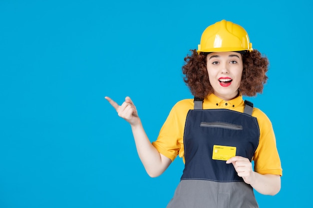 Constructor femenino en uniforme con tarjeta de crédito en un azul