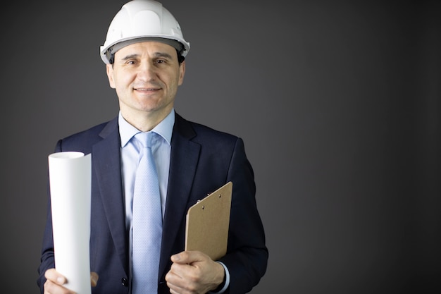 Constructor guapo positivo en ropa formal de casco tiene dibujo sonriendo