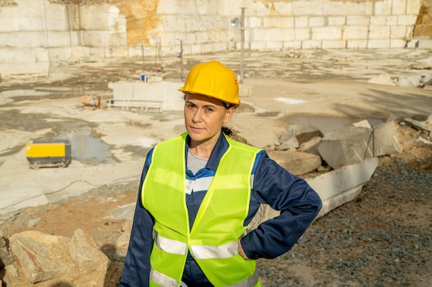 Constructor de hembras maduras en ropa de trabajo mirándote en el sitio de construcción