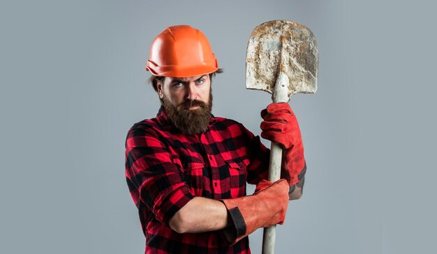 Constructor de hombre brutal en uniforme y casco con arquitectura de pala