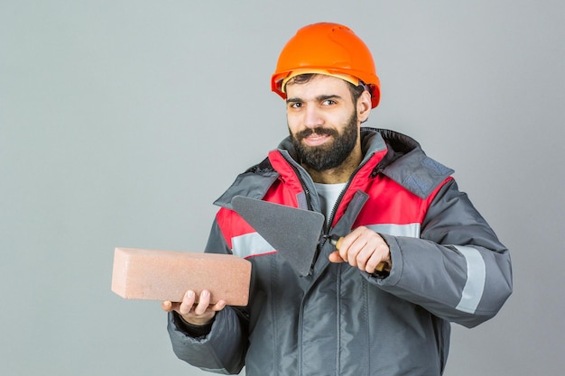 Constructor de hombre en ropa de invierno en estudio sobre fondo gris