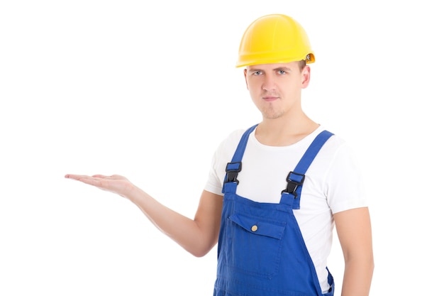 Constructor de hombre en uniforme azul y casco sosteniendo algo en la palma aislado sobre fondo blanco.