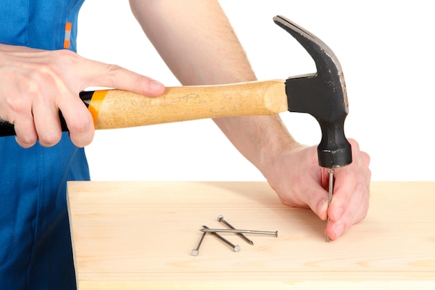 Constructor martillando clavos en el tablero aislado en blanco