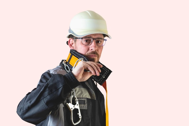 Constructor masculino barbudo amigable positivo en overoles y casco de seguridad y gafas mirando a la cámara sobre fondo aislado