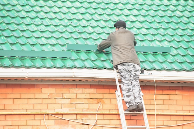 Foto constructor masculino instala protectores de nieve en el techo de la casa