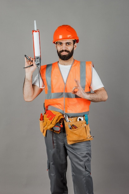 Constructor masculino de mediana edad en uniforme sobre fondo gris