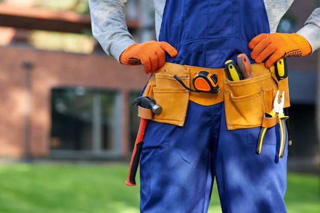 Constructor masculino en overol azul con cinturón de herramientas. Cerrar en el área de la cintura