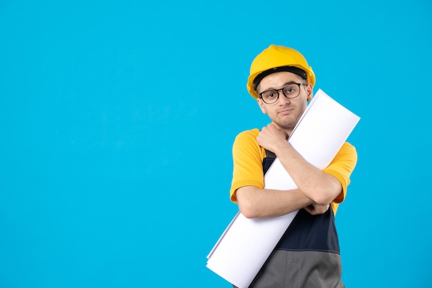 Constructor masculino de vista frontal en uniforme con plan de papel en azul