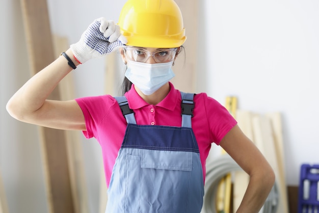 Constructor de mujer en casco amarillo y máscara protectora