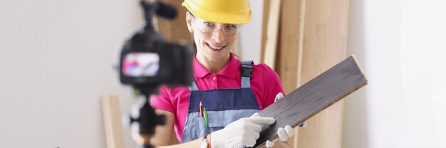 Constructor de mujer en casco de seguridad con tablero de madera delante de la cámara