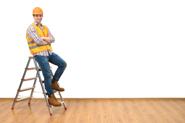 Foto el constructor de pie en la escalera en el fondo de la pared blanca