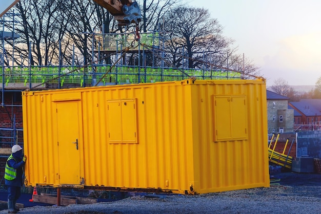 Constructor que instala el contenedor de la cabina de la oficina del sitio Instalaciones de bienestar en el sitio de construcción